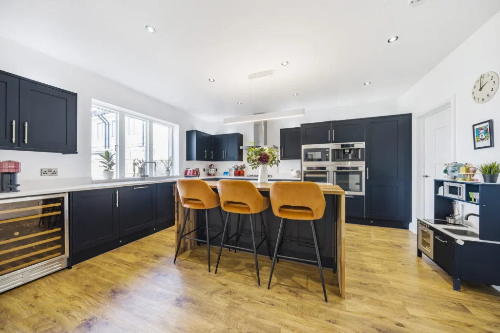 A clean kitchen with blue doors and a wooden floor